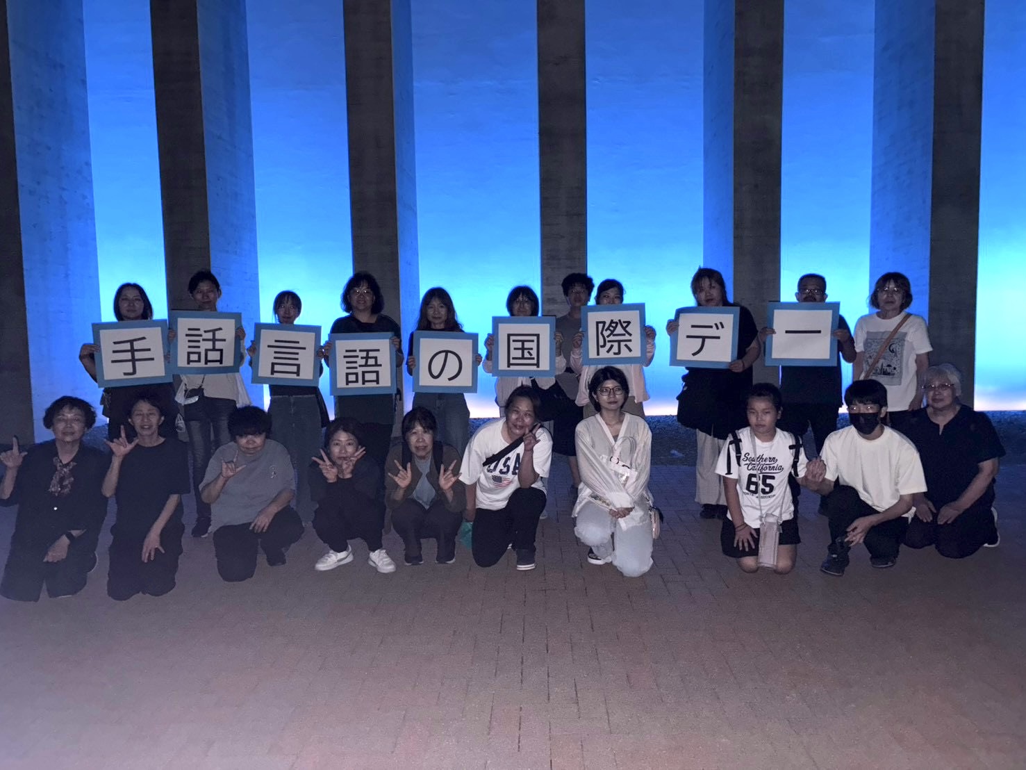ブルーライトアップの前で記念写真を撮る太子手話サークルぶらんこの皆さん